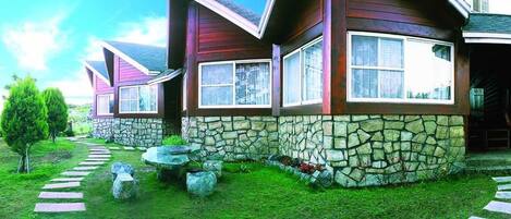 A modern house with stone walls and a stone pathway leading to the entrance.