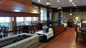 A restaurant with wooden tables and chairs, a stone wall, and a clock on the wall. - Liching Garden Villa (Ren'ai)