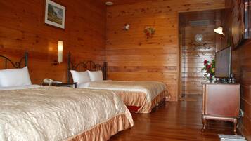 A wooden-paneled room with two beds, a nightstand, a lamp, and a dresser.