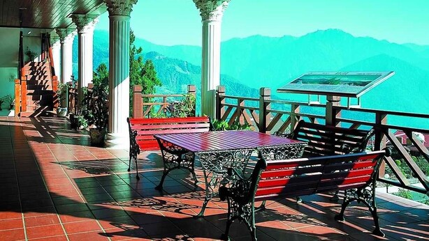 A covered terrace with red-tiled flooring, a table with chairs, and a view of mountains. - Liching Garden Villa (Ren'ai)