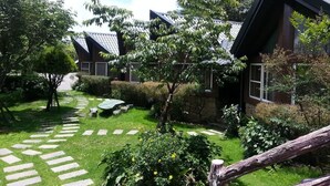 A courtyard with stone pathways, a small seating area, and a variety of trees and shrubs. - Liching Garden Villa (Ren'ai)