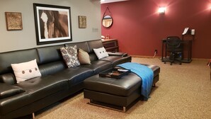 Ein Wohnzimmer mit einem schwarzen Ledersofa, einem Couchtisch und einer roten Akzentwand.