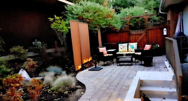 A patio area with a curved stone pathway, a wooden fence, and a seating arrangement with chairs and a table. - Close to UM & Downtown. Refurbished 1350 sq ft w/ Gym, Laundry, Kitchen, Patio. (Missoula)