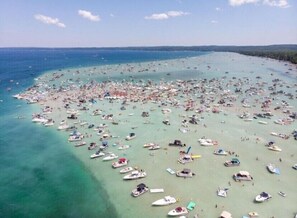 En vy över en fullsatt strand, tagen från luften, med många båtar och människor.