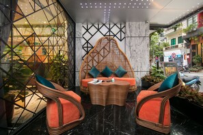 A lobby with wicker furniture, a marble floor, and a geometric wall design. - Aurora Premium - A Lifestyle Hotel (Hanoi)