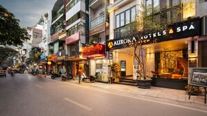 A street view of a hotel with a prominent sign for 'AURORA HOTELS & SPA'. - Aurora Premium - A Lifestyle Hotel (Hanoi)