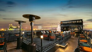 A rooftop bar with outdoor seating and a view of the city skyline at dusk. - Aurora Premium - A Lifestyle Hotel (Hanoi)