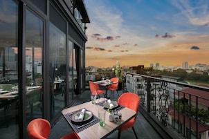 A dining area with a table set for two, overlooking a cityscape at sunset.