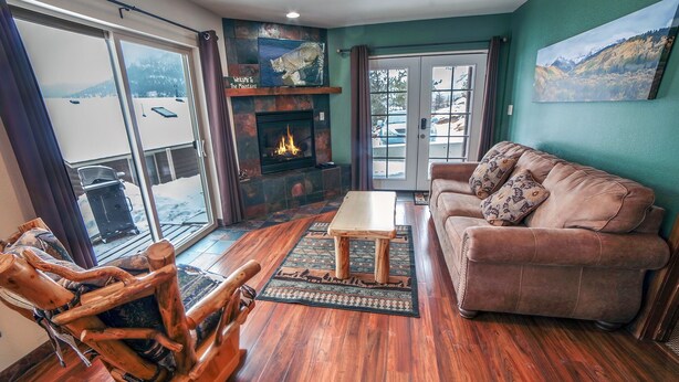 Una sala de estar acogedora con chimenea, un sofá de cuero y un sillón mecedor de madera.