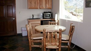 Una cocina con armarios de madera, una mesa redonda de madera y sillas.