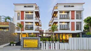 A modern hotel with a symmetrical facade, multiple balconies, and a well-lit entrance area. - December Hoi An Villa (Da Nang)
