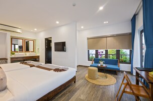 Una habitación de hotel moderna con una cama grande, un sofá, una mesa de comedor, un televisor y un baño con espejo y lavamanos.