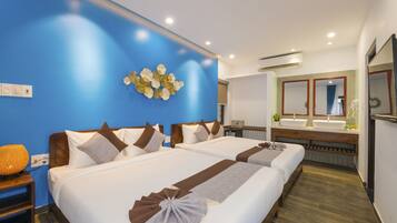 A hotel room with two beds, a large mirror, a vanity with two sinks, and a decorative wall piece.