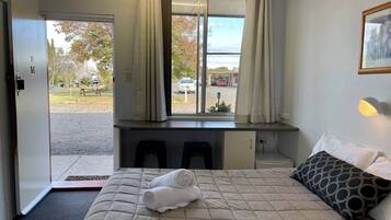 A hotel room with a bed, a desk, and a window with curtains.