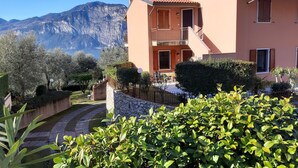 A Mediterranean-style building with a balcony, a stone pathway, and a view of mountains.