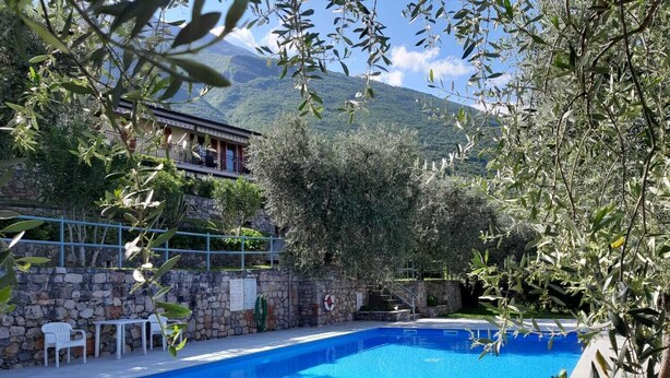 A swimming pool with a stone wall and a view of a mountain.