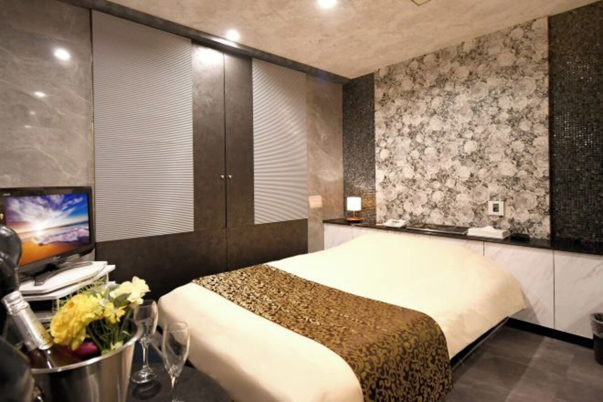A hotel room with a bed, a television, a minibar, and a decorative wall.