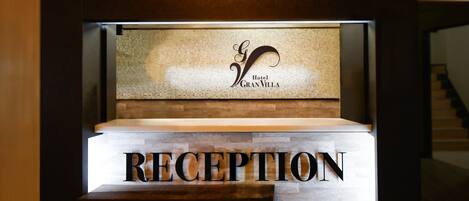 A reception desk with a sign that reads 'RECEPTION' and a mosaic wall above it.