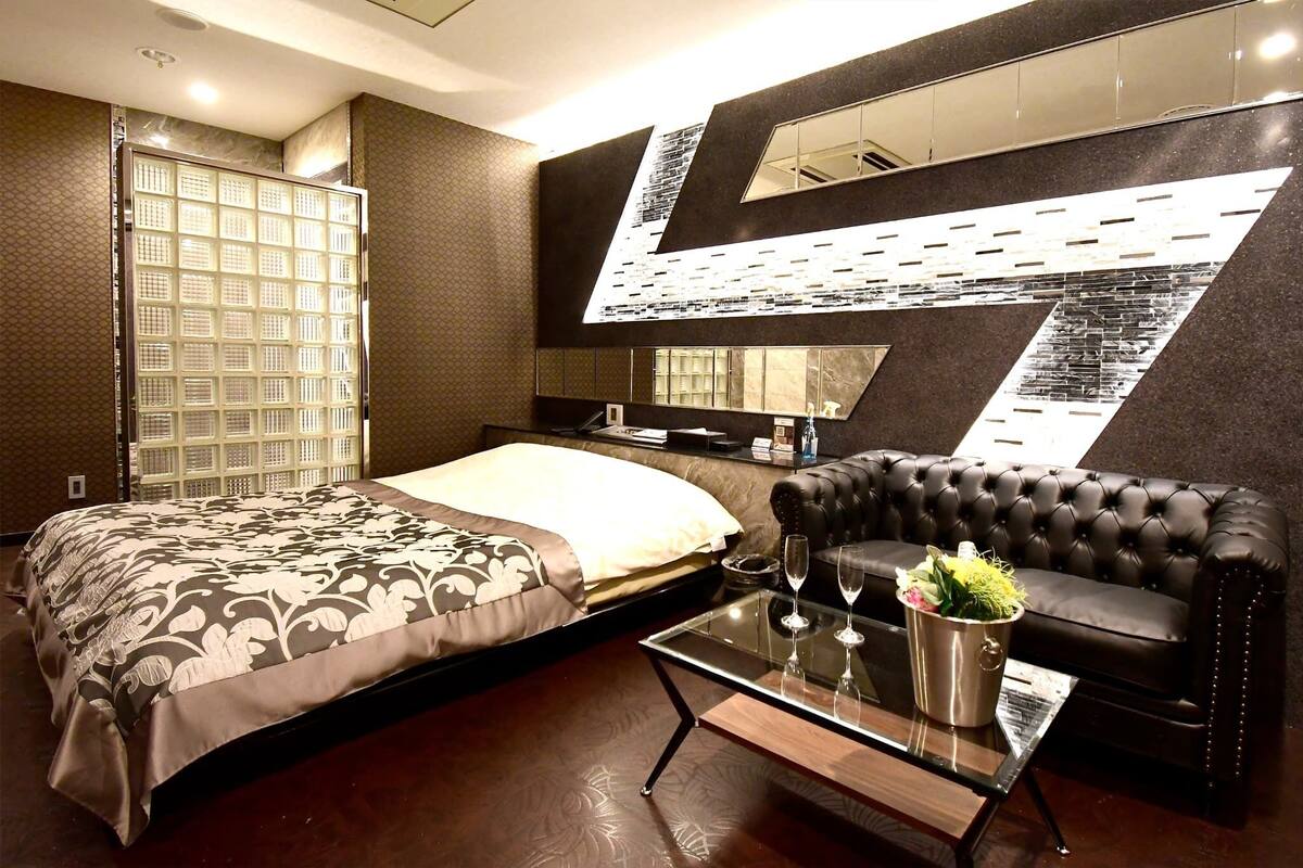 Una habitación de hotel moderna con una cama, un sofá, una mesa de centro de vidrio y un espejo grande.