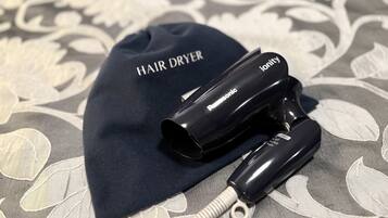 Un secador de pelo y una gorra con el texto 'HAIR DRYER' e 'ionity' sobre un fondo de tela estampada.