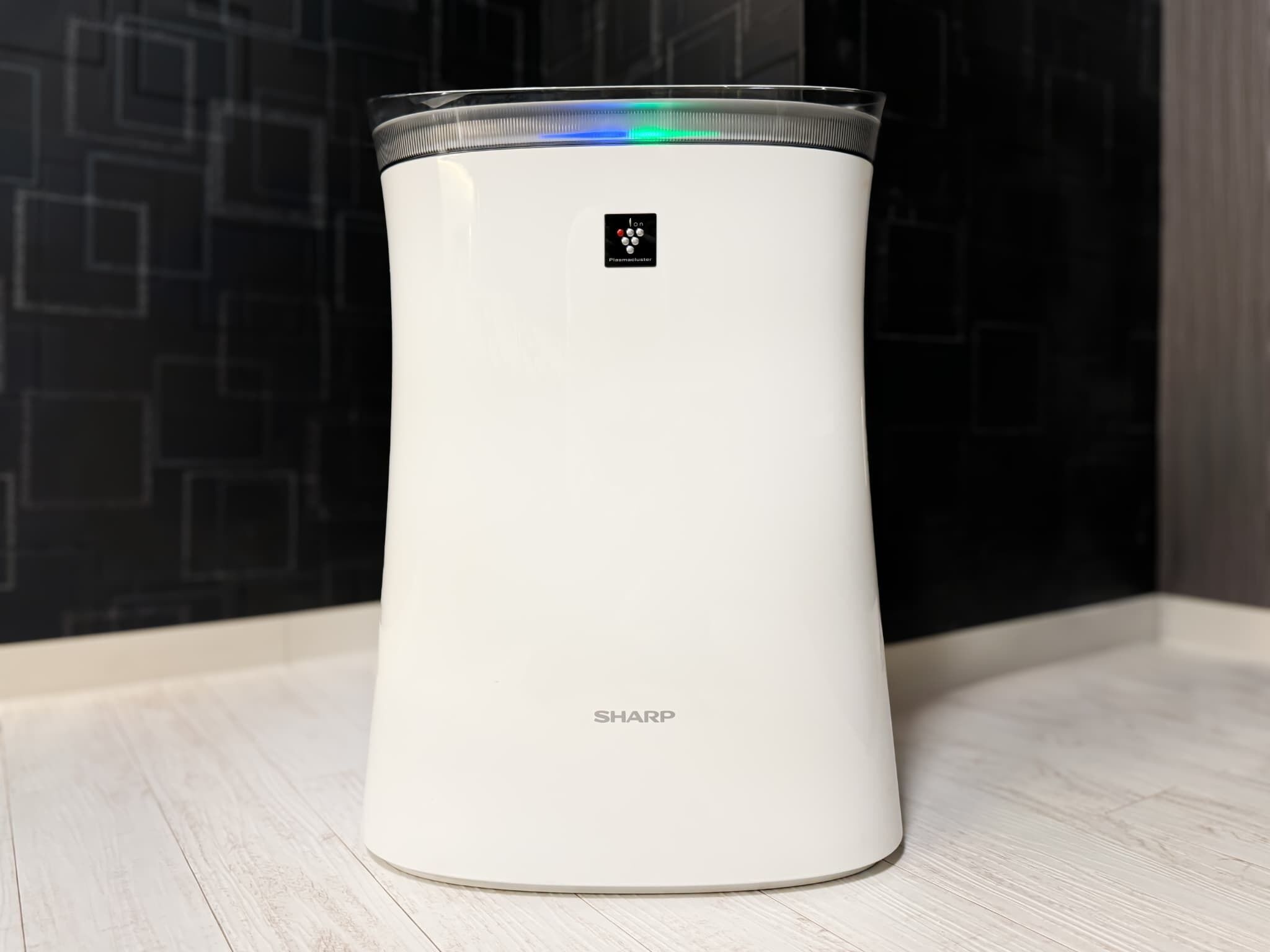 A white, cylindrical device with a control panel and the brand name 'SHARP' on a light-colored wooden surface.