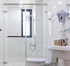 A modern bathroom with a glass-enclosed shower, a toilet, and a sink with a hairdryer mounted on the wall. - Art Ocean (Tainan)