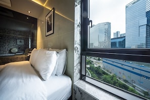 A hotel room with a bed, a marble wall, a framed picture, and a window with a city view. - MG Hotel Jonggak (Seoul)
