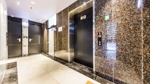 A modern elevator with a control panel, adjacent to a door with a keypad. - MG Hotel Jonggak (Seoul)