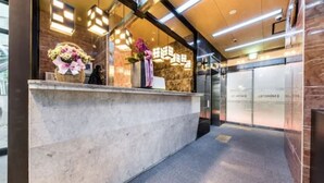 A hotel reception desk with a marble counter, floral arrangements, and a modern interior design. - MG Hotel Jonggak (Seoul)