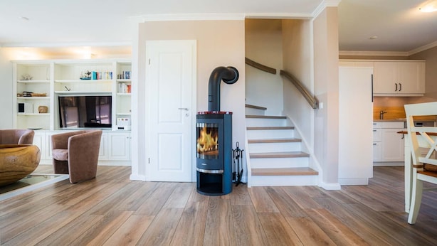 Una sala moderna con chimenea de leña, una escalera y una zona de cocina.