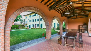 Un espacio al aire libre cubierto con arcos de ladrillo, una mesa de picnic y suelo de ladrillo.