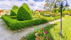 Un jardín bien cuidado con setos recortados, un sendero y un farol tradicional.
