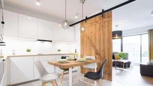 Una cocina moderna con armarios blancos, un panel de madera decorativo e iluminación colgante.