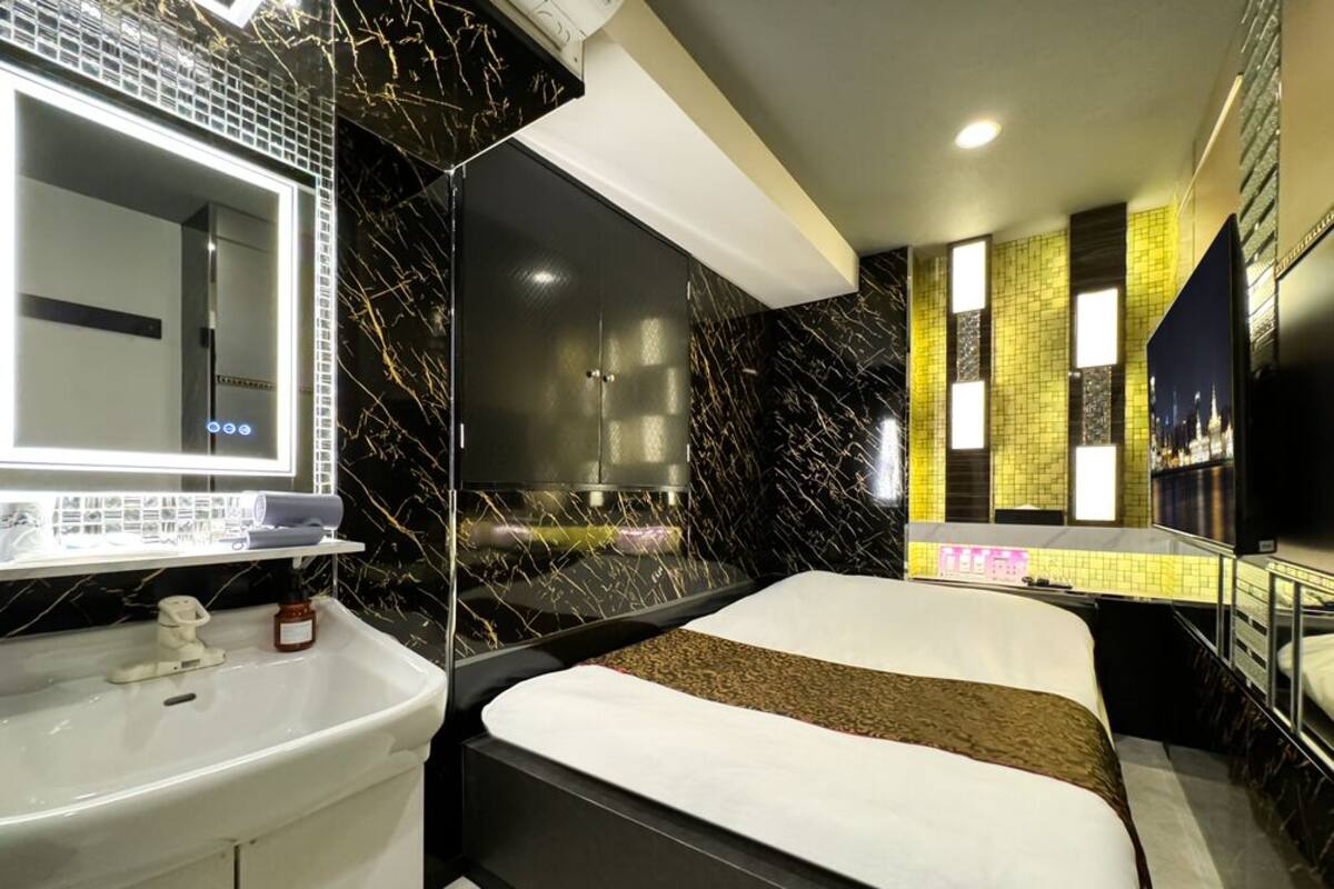 A modern bathroom with a large mirror, a white sink, and a black bathtub.