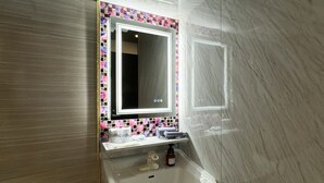 Un bagno con lavandino bianco, uno specchio e una parete rivestita di piastrelle.