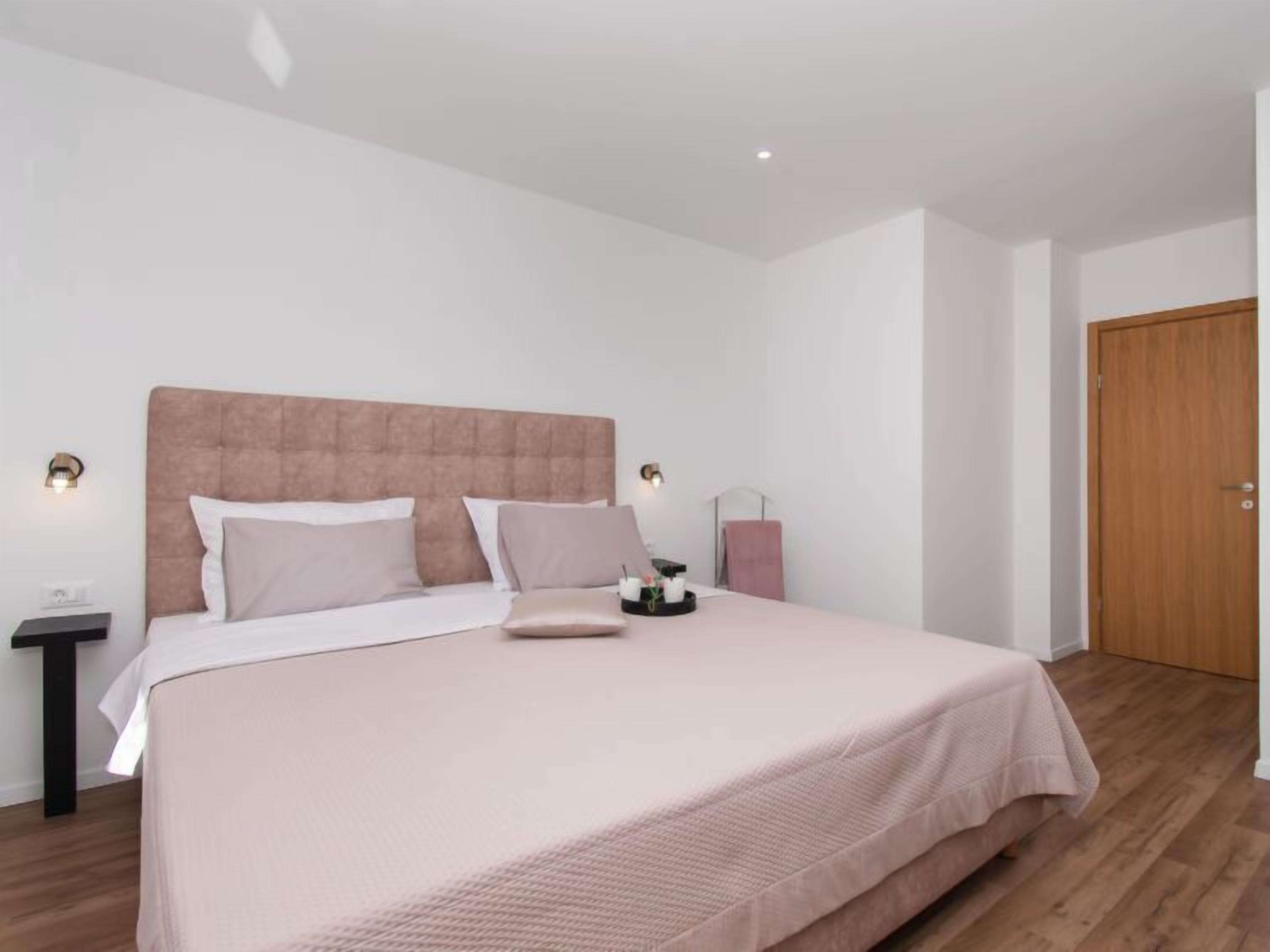 Une chambre à coucher moderne avec un grand lit, une table de chevet, une commode et une porte en bois.