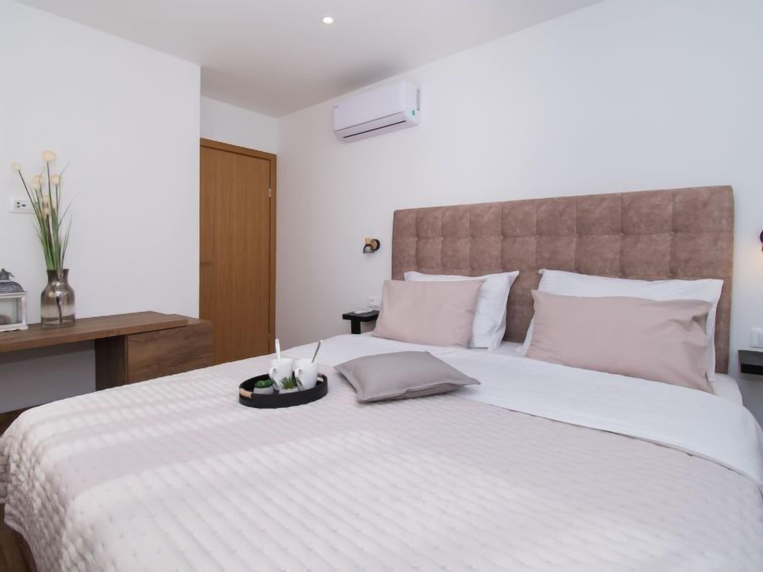 Una camera da letto ordinata con un letto grande, un comodino e un’unità di condizionamento dell'aria a parete.