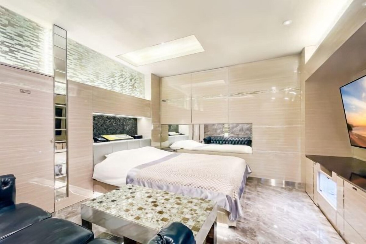 Une chambre d’hôtel moderne dotée d’un grand lit, d’un coin salon, d’une télévision et d’une salle de bain avec un miroir et un lavabo.