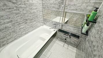 A modern bathroom with a large bathtub, a shower area, and a vanity with toiletries.