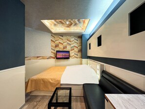 A modern room with a bed, a TV mounted on the wall, a small table, and a bench. - Hotel Century (Chiba)