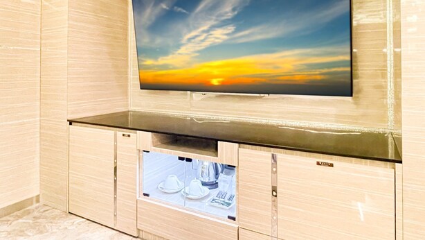 A modern bathroom with a large mirror, a vanity with a sink, and a framed picture of a sunset. - Hotel Century (Chiba)
