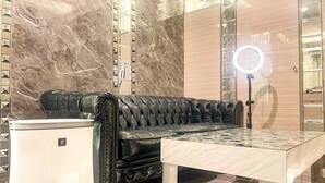 Un canapé en cuir noir à motifs capitonnés, une poubelle blanche et un sol à motifs de marbre.