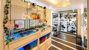 Un espace d’accueil d’hôtel où sont exposés divers produits d’accueil, notamment des shampoings, un arrangement floral et un comptoir avec des sacs.