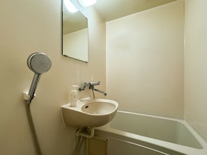 A bathroom with a sink, mirror, shower, and a bottle of hand soap. - Hotel Century (Chiba)