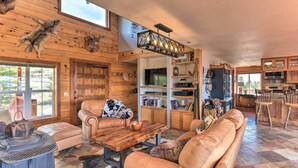 A rustic cabin interior with a wooden interior, leather furniture, a stone fireplace, and a kitchen area. - Secluded Cotopaxi Cabin w/ Panoramic Mtn Views (Cotopaxi)