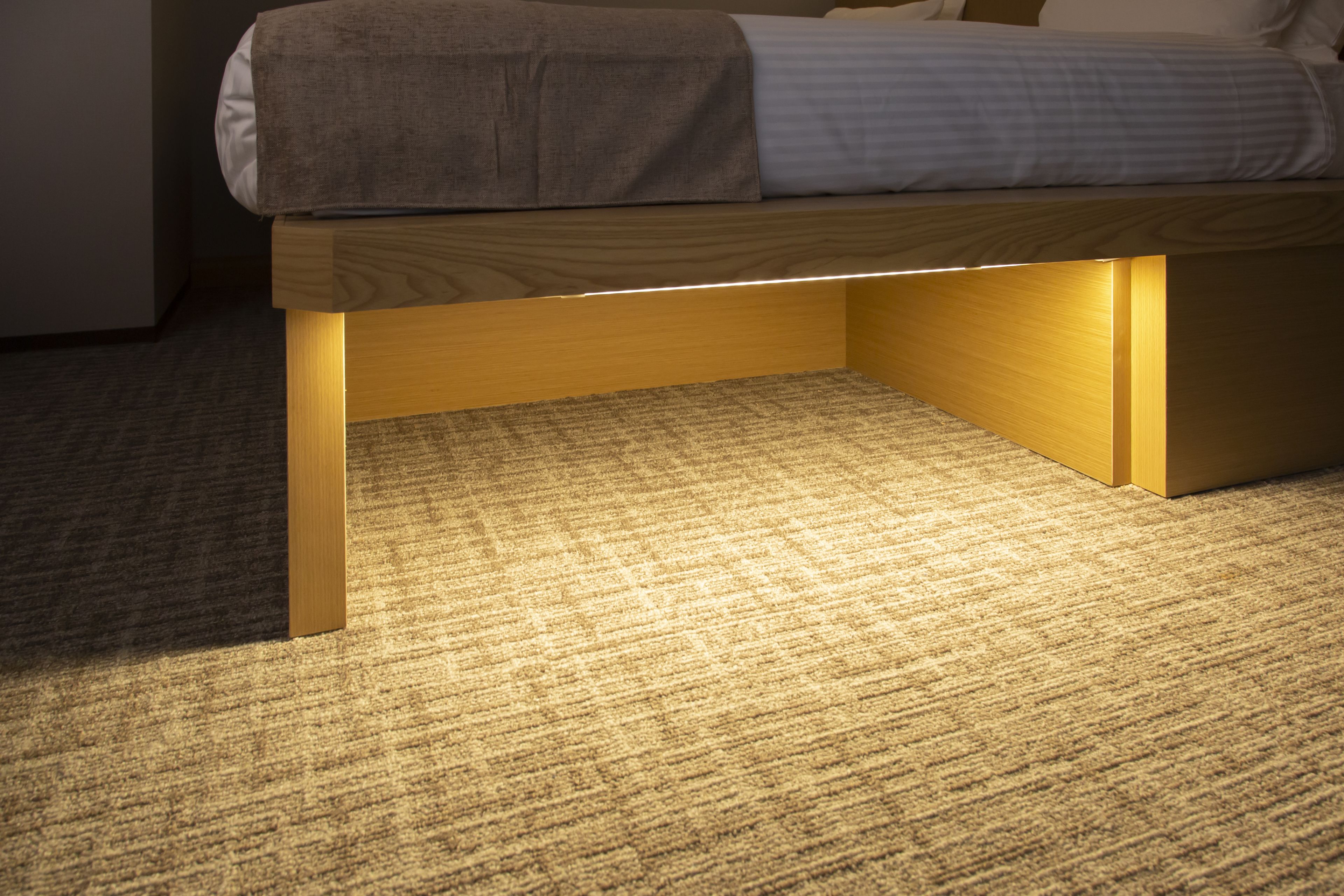 A bed with a wooden frame and a mattress on a carpeted floor.