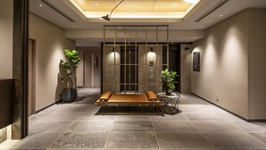 Un vestíbulo moderno con un banco de madera, plantas en macetas e iluminación colgante.