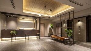 Un área de recepción moderna con mostrador de madera, asientos y plantas en macetas.