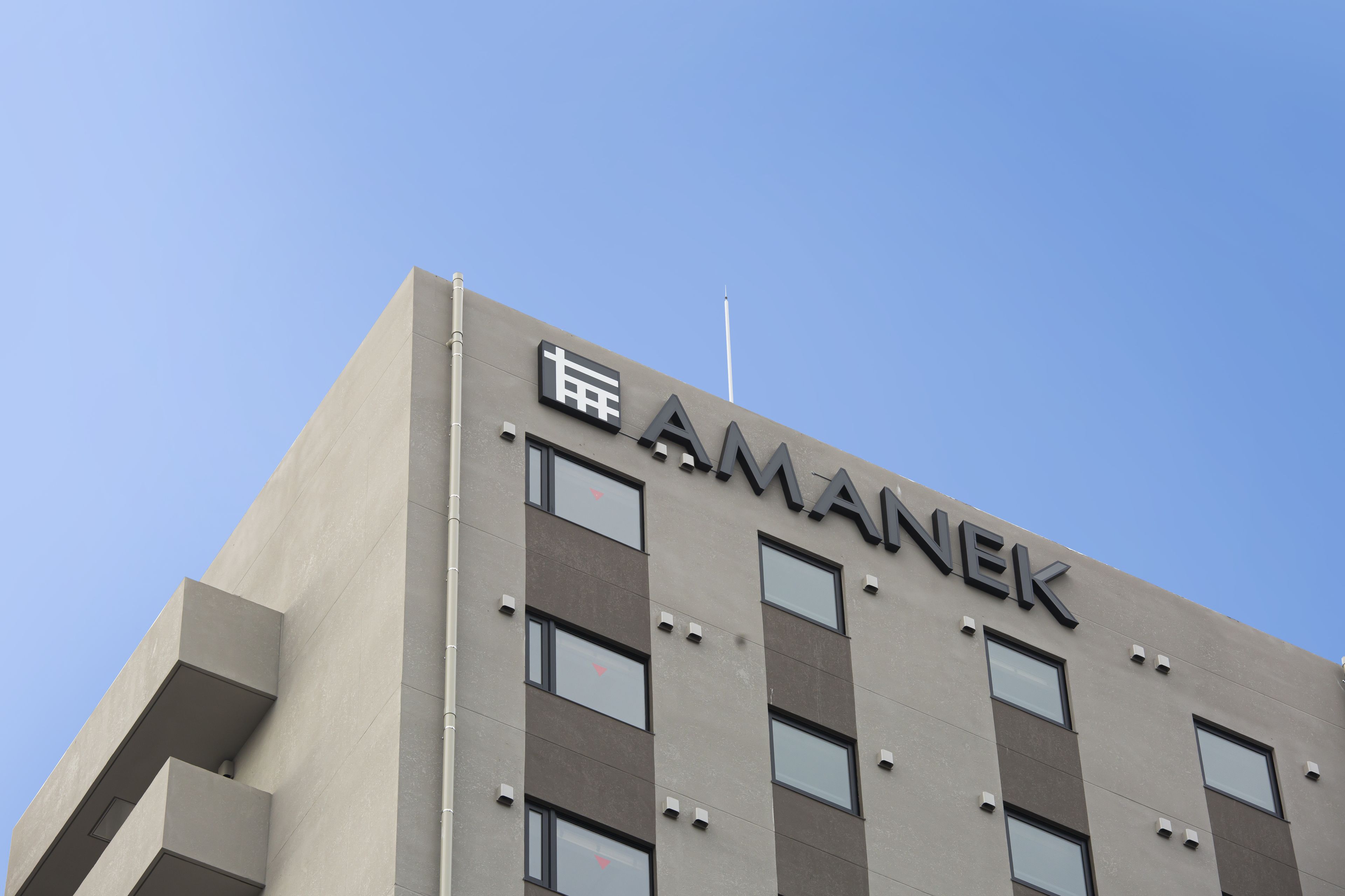 A building with the name 'AMANEK' prominently displayed on its facade.