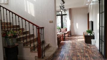 A staircase with a wooden handrail and black balusters, leading to a room with a patterned wall and a large window.